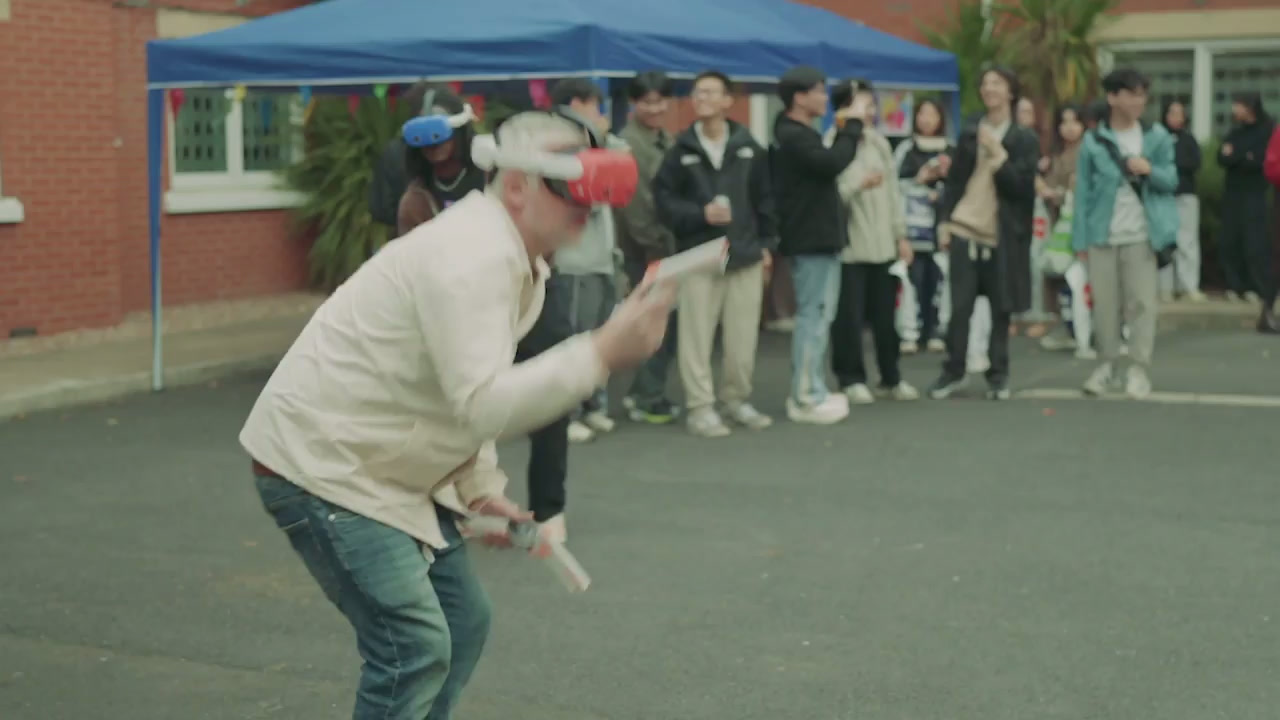 A player in a VR headset mid-game while a crowd watches at an outdoor event